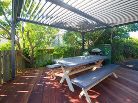 An outdoor dining area with a table, benches, and a grill at The Bach - Kaikoura Holiday Home, Kaikoura