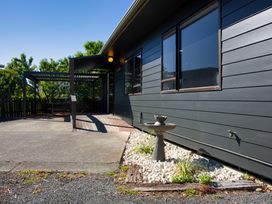 An outdoor area with a house exterior and a pergola at The Bach - Kaikoura Holiday Home in Kaikoura