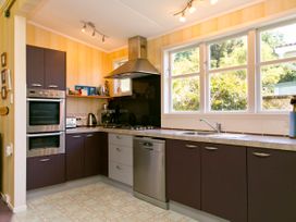 A kitchen with cabinets and appliances at The Trout House - Turangi Holiday Home