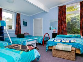 A bedroom with multiple beds and a window at The Trout House - Turangi