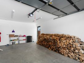 A garage with a pile of firewood and a shelf against the wall at Northlake Hideaway - Wanaka