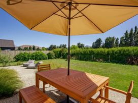 A patio area with a wooden table and umbrella at Northlake Hideaway - Wanaka