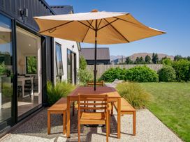 A patio with a table and chairs under an umbrella at Northlake Hideaway - Wanaka
