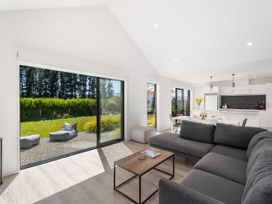 A living room with a sliding door and kitchen at Northlake Hideaway - Wanaka Holiday Home, Wanaka