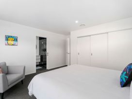 A bedroom with a bed and an armchair at Northlake Hideaway - Wanaka Holiday Home Wanaka