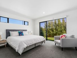 A bedroom with a bed and a chair at Northlake Hideaway - Wanaka Holiday Home Wanaka