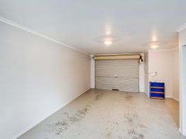 A garage with a roller door and shelving at Napier Holiday Home in Napier