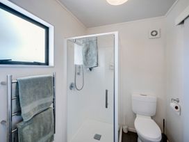 A bathroom with a shower, toilet, and towel rack at Napier Holiday Home, Napier