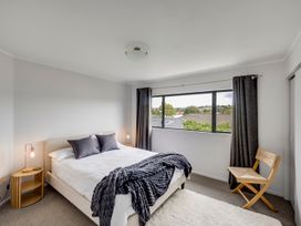 A bedroom with a bed and a chair at Napier Holiday Home, Napier