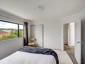 A bedroom with a bed and a chair at Napier Holiday Home in Napier