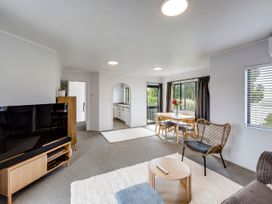 A living room with a television, sofa, dining table, and kitchen at Napier Holiday Home in Napier