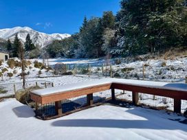 A snowy outdoor area with mountains and a wooden bench at Cedarwood Retreat - Castle Hill