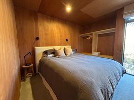 A bedroom with a bed, lamp, and clothes rack at Cedarwood Retreat - Castle Hill