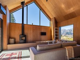 A living room with a stove, sofa, and large windows at Cedarwood Retreat - Castle Hill