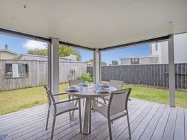 An outdoor dining area with a table and chairs at Whangamata Holiday Unit in Whangamata