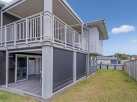 An outdoor area with a balcony and grass at Whangamata Holiday Unit in Whangamata