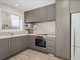A kitchen with cabinets, stove, oven, microwave, sink, and refrigerator at Whangamata Holiday Unit in Whangamata
