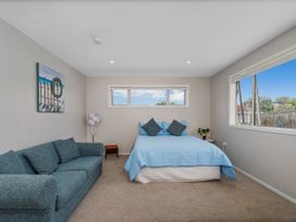 A bedroom with a bed and sofa at Whangamata Holiday Unit Whangamata