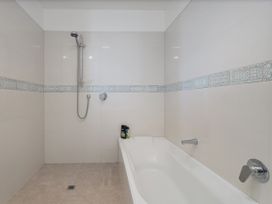 A bathroom with a shower and bathtub at Whangamata Holiday Unit in Whangamata