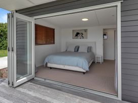 A bedroom with a bed and a bedside table at Mangawhai Holiday Unit in Kaiwaka