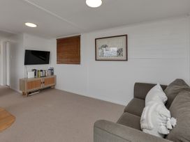 A living room with a sofa and television at Mangawhai Holiday Unit in Kaiwaka