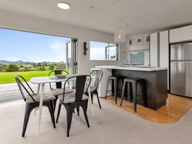 A kitchen with a dining table and chairs at Mangawhai Holiday Unit in Kaiwaka