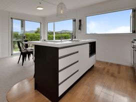 A kitchen with a central island sink and chairs at Mangawhai Holiday Unit in Kaiwaka