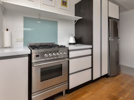 A kitchen with stove and refrigerator at Mangawhai Holiday Unit in Kaiwaka