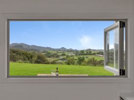A window view of mountains and landscape with a table and wine at Mangawhai Holiday Unit in Kaiwaka