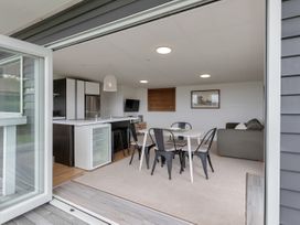 A living room and kitchen area with a dining table and chairs at Mangawhai Holiday Unit in Kaiwaka