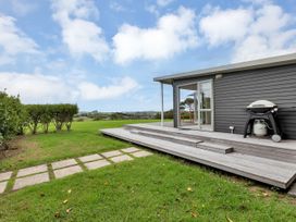 A deck with a barbecue and pathway at Mangawhai Holiday Unit in Kaiwaka