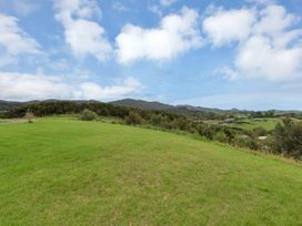 A grassy area with trees and mountains in the background at Mangawhai Holiday Unit in Kaiwaka