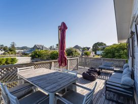 A deck with a table and seating area at Pauanui Holiday Home in Pauanui