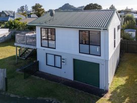 An exterior view of a two-story house with a garage and deck at Pauanui Holiday Home in Pauanui