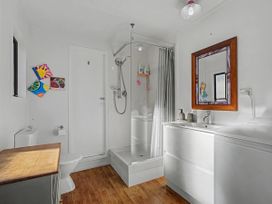 A bathroom with shower, toilet, sink, and washing machine at Pauanui Holiday Home, Pauanui