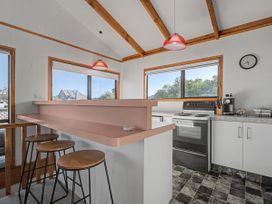 A kitchen with a counter and bar stools at Pauanui Holiday Home in Pauanui