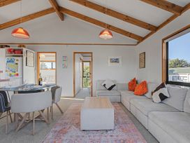 A living room with a sofa and dining area at Pauanui Holiday Home in Pauanui