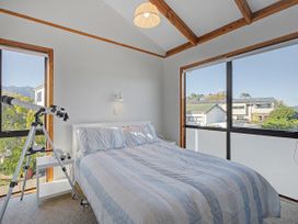 A bedroom with a bed and telescope at Pauanui Holiday Home in Pauanui