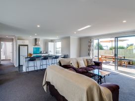 A living room with a sofa and kitchen area at SeaRenity - Waimarama Holiday Home Havelock North