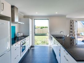 A kitchen with appliances and a view of the garden at SeaRenity - Waimarama Holiday Home Havelock North