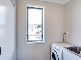 A laundry room with a washing machine and window at SeaRenity - Waimarama Holiday Home Havelock North