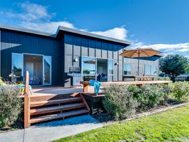 An outdoor area with a deck, grill, and seating at SeaRenity - Waimarama Holiday Home Havelock North