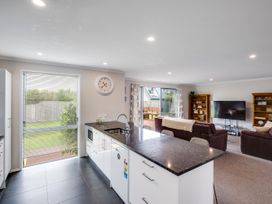 A kitchen with a view of the living area and a clock at SeaRenity - Waimarama Holiday Home Waimarama