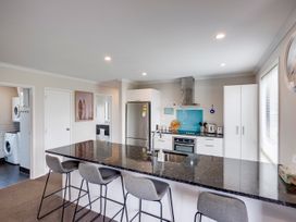 A kitchen with a kitchen island and stools at SeaRenity - Waimarama Holiday Home in Waimarama
