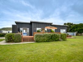 A house with a deck and an umbrella at SeaRenity - Waimarama Holiday Home Waimarama