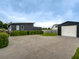 A house and garage with a driveway and grass area at SeaRenity - Waimarama Holiday Home, Waimarama
