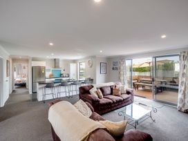 A living room with a sofa, coffee table, kitchen area, and dining table at SeaRenity - Waimarama Holiday Home, Waimarama