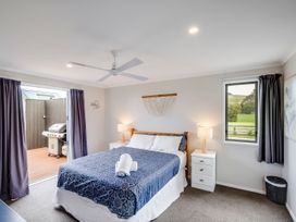 A bedroom with a bed and windows at SeaRenity - Waimarama Holiday Home Waimarama