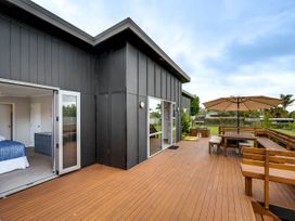 A deck with an umbrella and outdoor furniture at SeaRenity - Waimarama Holiday Home Waimarama