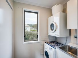 A laundry room with a washing machine and drying machine at SeaRenity - Waimarama Holiday Home in Waimarama